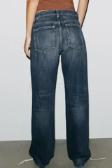 Pantalón de jean celeste claro, de tiro bajo, corte wide leg y largo hasta el tobillo. Tiene cinco bolsillos, cierre frontal con cremallera y botón metálico.