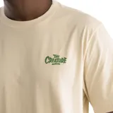 Remera color beige con logo de la marca Creature en el pecho.