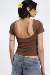 Top blanco de textura arrugada, con cuello redondo y mangas cortas.