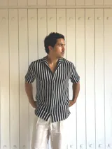 Camisa de hombre tejida a rayas verticales blancas y negras, de manga corta y cuello solapa.