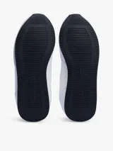 Zapatillas Tommy Hilfiger blancas de estilo running, con suela dentada fina y logo de la marca en el lateral.