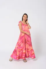 Vestido largo con volados en la falda y tirantes ajustables, en tonos rosas y naranjas con patrón abstracto.
