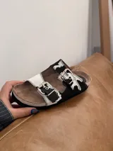 Sandalias con estampado de vaca, con forro de cuero y hebillas plateadas.