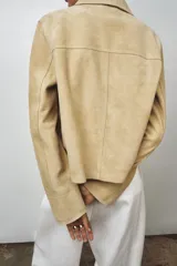 Chaqueta de mujer realizada en piel de ante color beige. Tiene cuello solapa, manga larga, bolsillos de plastrón en delantero y cierre frontal con botones.