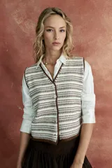 Chaleco tejido color blanco con rayas horizontales marrones, cuello en V y cierre frontal con botones.