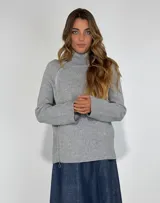 Campera de punto color beige, con cuello alto con cierre de cremallera lateral y mangas largas.
