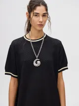 Vestido corto negro de tejido calado, con cuello redondo y mangas cortas con ribete en contraste.