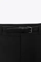 Falda pantalón corta negra de tiro alto con cinturón y hebilla metálica.