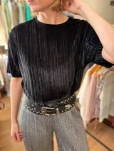Blusa negra de terciopelo plisado con mangas cortas y cuello redondo.