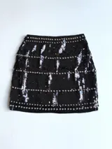 Minifalda negra de lentejuelas con tachas plateadas y cintura elastizada.