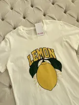 Remerón blanco de algodón con estampa de un limón con hojas y la palabra "LEMON" en amarillo y negro.