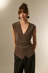 Top negro de manga corta, escote en V pronunciado, con diseño cruzado tipo wrap y ajuste lateral con apliques dorados.