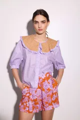 Short sastrero naranja con estampado floral en tonos lila, de tiro alto y corte holgado.