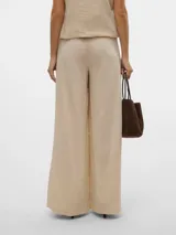 Pantalón sastrero color crema de tiro medio con pierna ancha y pliegue marcado.