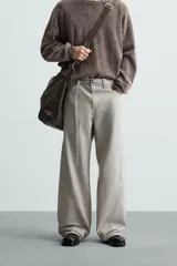 Pantalón de algodón color beige claro, estilo relaxed fit, con cintura ajustable mediante cinturón de tela a juego. Presenta cinco bolsillos, bolsillos laterales de vivo y costuras laterales giradas hacia adelante.