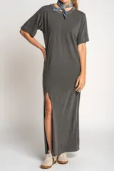 Vestido largo gris oscuro de algodón, con cuello redondo y mangas cortas. Presenta un tajo lateral alto.