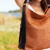 Cartera negra de simil cuero con apertura superior con cierre. Tiene detalle frontal en costura, dos bolsillos internos, un bolsillo divisor en el forro y bolsillos laterales con cierre. Incluye correa larga regulable.