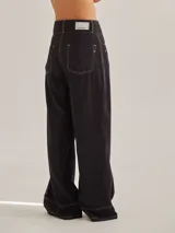 Pantalón negro de tiro medio alto, corte palazzo, con bolsillos delanteros y traseros.