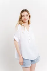 Camisa azul de lino con escote en V abotonado, bolsillo frontal y mangas 3/4 con trabilla.