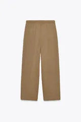 Pantalón color marrón claro, de tiro medio, corte ancho y largo tobillero. Cuenta con cintura elástica ajustable con cordones y bolsillos laterales ocultos en la costura.