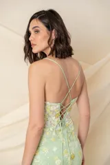 Vestido largo de tul bordado con motivos florales en tonos verdes. Tiene breteles finos cruzados en la espalda y tajo lateral.