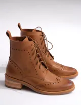 Bota corta de cuero color marrón claro, con cordones y detalles de perforaciones. Tiene un pequeño taco de madera.