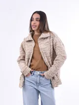 Campera de abrigo de tejido tipo sherpa o borrego, color beige claro con estampado animal print sutil en tonos más oscuros. Tiene cuello alto y cierre frontal.