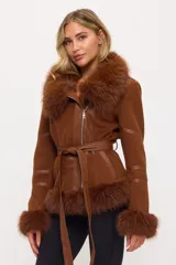 Campera tipo tapado acinturado color marrón, con cuello, puños y bajo de piel sintética. Presenta cierre frontal, detalles de cuero sintético en las mangas y un cinturón anudable del mismo material.