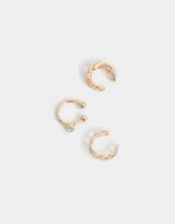 Set de tres cuffs dorados con diferentes diseños: uno liso con bolitas y strass, otro con forma de cadena gruesa y otro con forma de cadena fina.