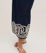 Pollera recta de largo midi en color azul marino, confeccionada en tejido de cambraia de algodón y lino. Presenta un bordado geométrico en color crema en el ruedo, cierre de cremallera y abertura central en la parte trasera.