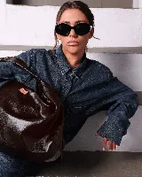 Bolso marrón oscuro de cuero sintético con forma ovalada y asa corta.