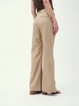 Pantalón de vestir color beige, de corte palazzo, con cintura alta y detalle de botones en el ruedo.