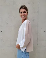 Blusa de manga larga, color beige y blanco, con pespuntes contrastantes y un corte suelto.