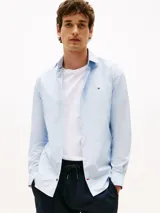 Camisa celeste de popelina con tecnología flex, corte slim, cuello abotonado, cierre con botones, manga larga y logo de Tommy Hilfiger bordado en el pecho.