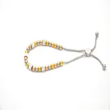 Pulsera dorada con cuentas redondas y cilíndricas con incrustaciones de strass, ajustable con cierre corredizo.
