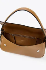 Bolso bandolera color camel con doble asa: una asa larga regulable y una asa de hombro. Tiene un bolsillo interior con cierre mediante cremallera metálica y detalle de solapa con cierre imantado.