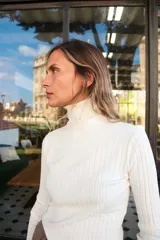 Polera blanca de algodón acanalado, de cuello alto y manga larga.