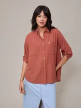 Camisa color ladrillo de algodón y lino, con cuello clásico, cierre frontal con botones, mangas 3/4 con trabilla y dos bolsillos de parche en el pecho.
