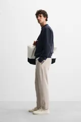 Pantalón de jogging color beige confeccionado en tejido de mezcla de algodón. Cuenta con cintura elástica ajustable con cordón, bolsillos frontales y traseros.