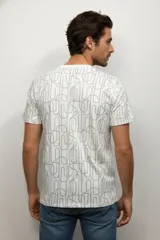 Remera de manga corta color beige con cuello redondo, confeccionada en algodón y con un estampado de rayas horizontales discontinuas en color marrón oscuro.