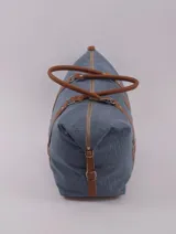 Bolso de viaje negro con detalles en cuero marrón, doble asa de mano y cierre superior con cremallera.