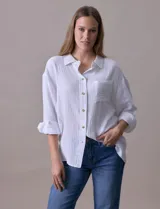 Camisa blanca de algodón con textura arrugada, cuello con solapa, abertura central con botones y bolsillo aplicado en el pecho. Mangas largas con largo regulable mediante presilla y botón.