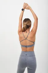 Top deportivo color beige con banda inferior azul y tirantes finos azul marino. Espalda cruzada con doble tira.