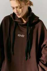 Buzo marrón de frisa con capucha y bolsillos delanteros. Corte oversize, recortes laterales y doble cordón con puntera de goma. Estampa en frente y espalda realizada en serigrafía con diseño de llavero con dijes.