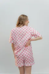 Conjunto de pijama de algodón a rayas verticales rosas y blancas, con detalles en celeste. Incluye camisa de manga corta con botones y bolsillo en el pecho, y shorts con cintura elástica.