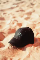 Gorra negra con logo bordado de una ola y la frase "Glassy Waves" en color celeste.