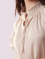 Blusa color beige de gasa estampada, marca Alex & Lili. Tiene cuello fruncido, escote en V con lazo y mangas cortas con volados.