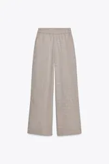 Pantalón ancho de tiro alto, color beige jaspeado, con cintura elástica y bolsillos delanteros.