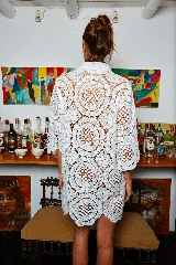 Camisa blanca de tela calada con círculos, corte holgado y mangas cortas.