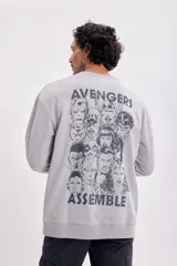 Buzo deportivo gris con cuello redondo y mangas largas. Estampado frontal con el texto "Avengers Assemble" en azul.